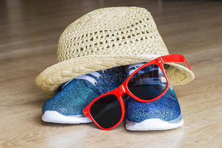 蓝色明亮的运动鞋和带红色太阳镜的草帽