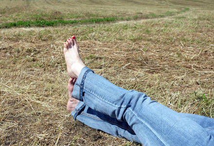 雌性赤脚，在草地上的干草上有红色的指甲