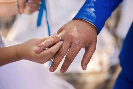 新娘和新郎旁边，新娘把结婚戒指送给新郎，男女手拿结婚戒指