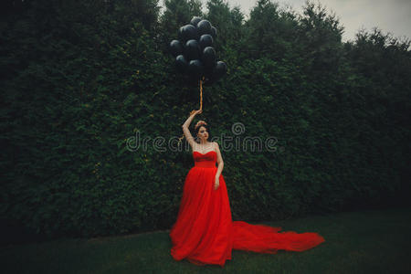 穿着红色连衣裙和黑气球的漂亮女人