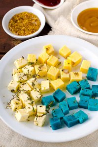 奶酪拼盘，果达，费塔，蓝色Pesto奶酪在白色盘子与草药，橄榄油，石榴和芥末酱