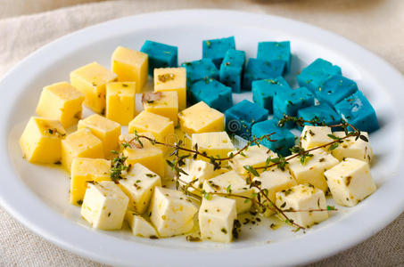 奶酪拼盘，果达，费塔，蓝色Pesto奶酪在白色盘子与草药，橄榄油，石榴和芥末酱