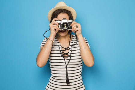 时尚年轻女孩用旧相机制作照片。 蓝色背景