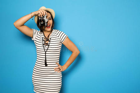 时尚年轻女孩用旧相机制作照片。 蓝色背景