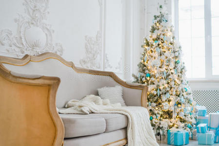 平静的室内豪华家居客厅装饰圣诞树和礼物，沙发上盖着毯子。 选择性聚焦