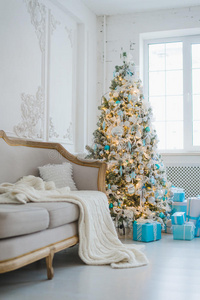 平静的室内豪华家居客厅装饰圣诞树和礼物，沙发上盖着毯子。 选择性聚焦