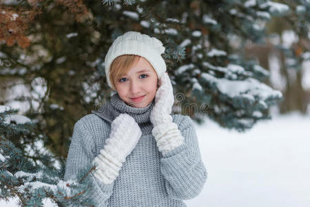 冬天雪林里戴着白色帽子和手套的漂亮女孩