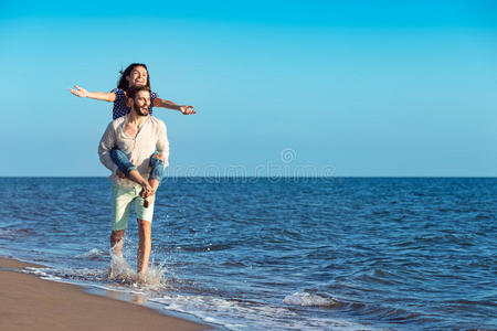 英俊的男人在海滩上还给他的女朋友