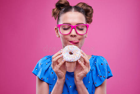 开朗的女孩吃甜甜圈舔嘴唇