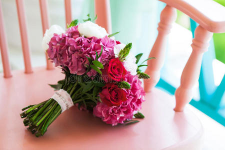 美丽的婚礼花束，玫瑰和牡丹在粉红色的椅子上