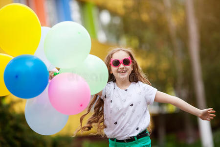 小女孩穿着明亮的衣服玩气球的特写肖像。