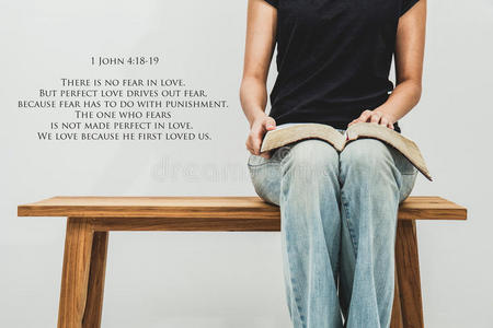 随便的年轻女人拿着一本开放的圣经1约翰41819在她的腿上
