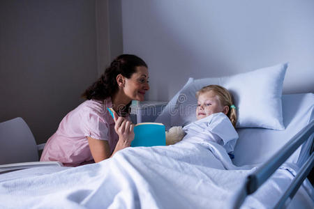 和她妈妈在病床上看书的女孩