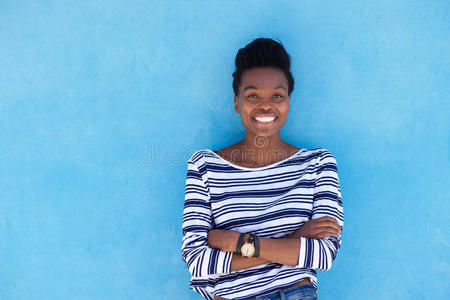 黑色的女人微笑着，双臂交叉在蓝色的背景上