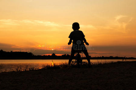 男孩玩和骑自行车日落背景