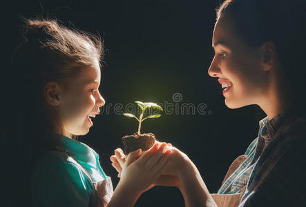 成人和儿童抱着绿色的芽。