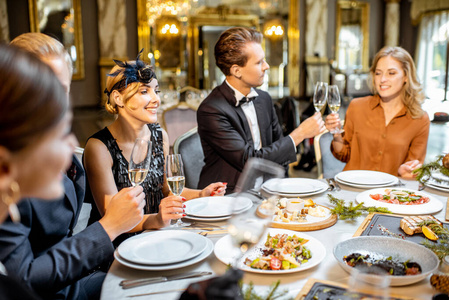 Elegantly dressed people having a festive dinner indoors