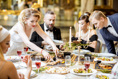 Elegantly dressed people having a festive dinner indoors