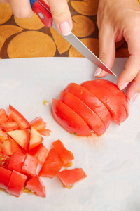 在白色的砧板上切新鲜成熟的西红柿