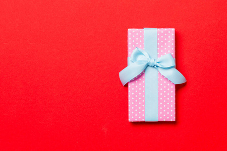 用红色背景的蓝色丝带纸包装的圣诞或其他节日手工礼品。礼品盒，彩桌上的礼品装饰，带复印空间的顶视图