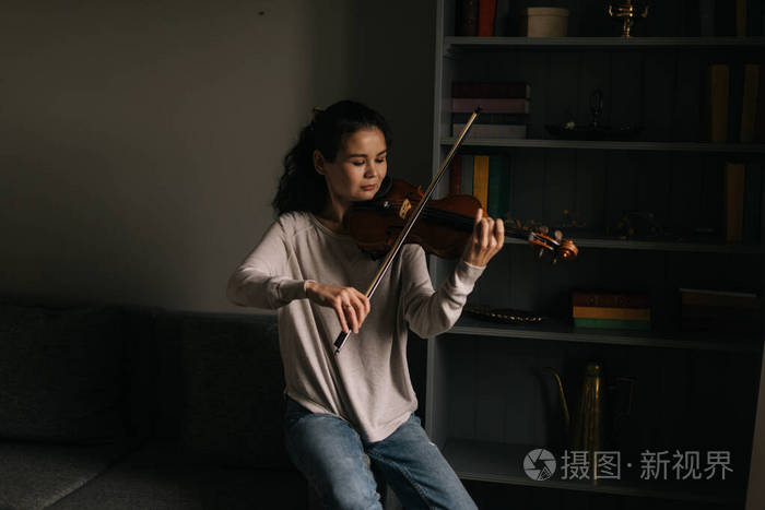 年轻的小提琴手在家里拉小提琴