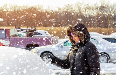 一个寒冷的冬日，一位年轻女子在他的车上扫雪