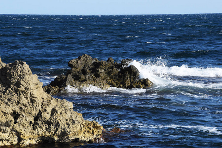海水拍打着岩石，浪花飞向不同的方向