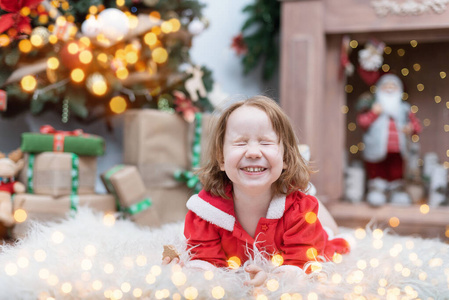 圣诞树旁的女孩闭着眼睛许愿。