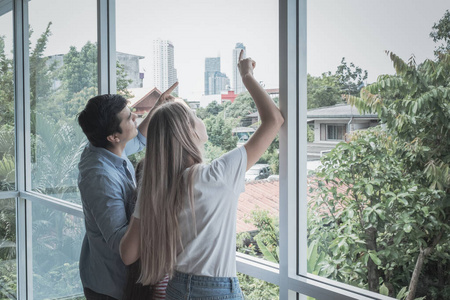 back view of father and mother with daughter standing at window 