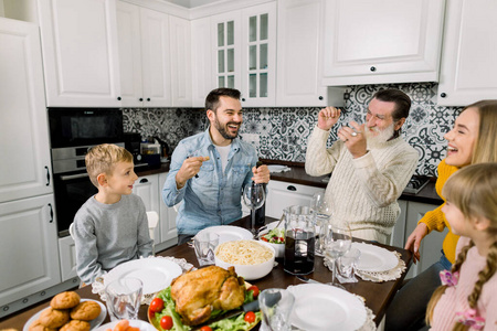 美丽幸福的家庭一起庆祝感恩节。爸爸打开一瓶红酒，爷爷笑了