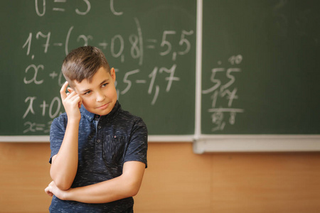 可爱的男孩站在教室黑板的背景上。教育。小学