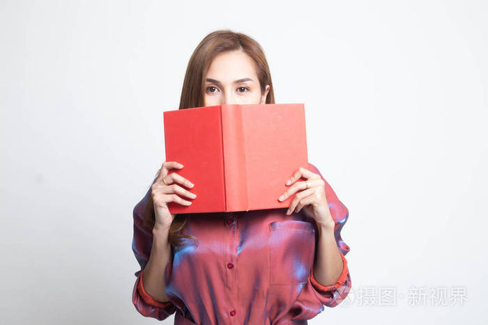 一位年轻的亚洲妇女拿着一本书遮住了她的脸