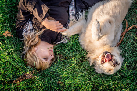 夕阳下，美丽的白种女人和她的金色拉布拉多猎犬躺在草地上