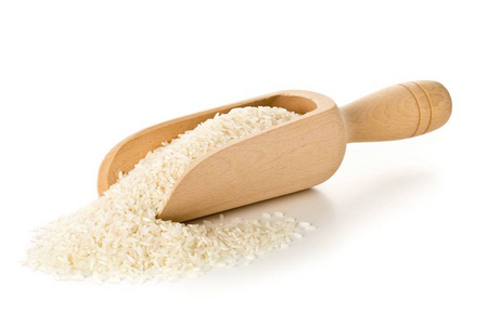 Heap of white uncooked, raw long grain rice in wooden scoop 