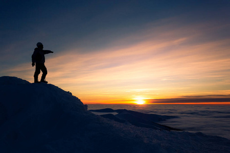一个人站在冬日的山顶上，日落
