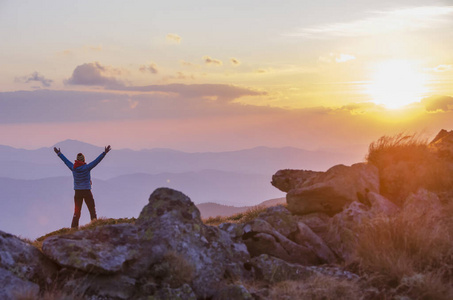 Lone tourist enjoying an amazing sunset with raised arms. 