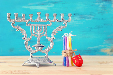 犹太节日光明节的宗教图像，带有烛台传统烛台和旋转顶部在木制桌子和蓝色背景上