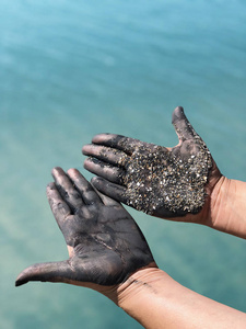 双手在泥泞的沙滩上，在水的背景下。