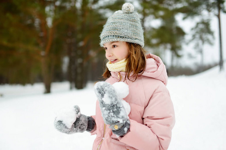 可爱的小女孩在美丽的冬季公园里玩耍。可爱的孩子在雪地里玩耍。有孩子的家庭冬季活动。
