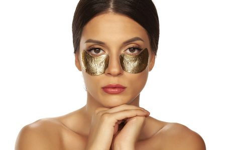 Young beautiful woman posing with golden patches under her eyes 