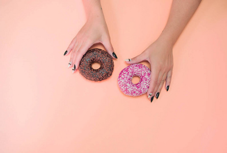 开胃甜甜圈，彩色背景，女性手和美丽的指甲。