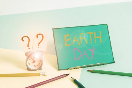写着地球日的便条。商业照片展示了全球生态环境保护庆典小型闹钟旁边的固定在柔和背景。