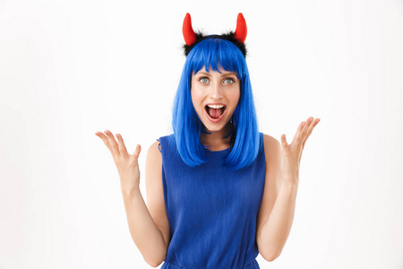 可爱的高兴的女人戴着蓝色假发和玩具恶魔的角尖叫着举起双手