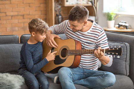 父亲和他的小儿子在家弹吉他图片