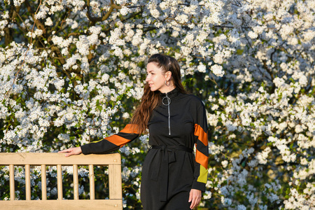 girl on the background of a blossoming apple tree. in black clot