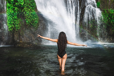 Young slim brunette woman with curly hair enjoying in lagoon of 