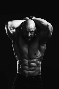 黑白肖像的秃头无袖男健美运动员与完美的六包提示运动和训练。照片