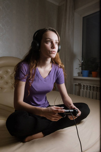 快乐的女人在玩电子游戏，坐在床上握着操纵杆。