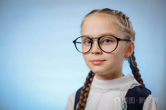 蓝色背景上戴眼镜的迷人小女孩的肖像