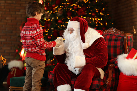 小男孩在圣诞树旁用饼干招待圣诞老人
